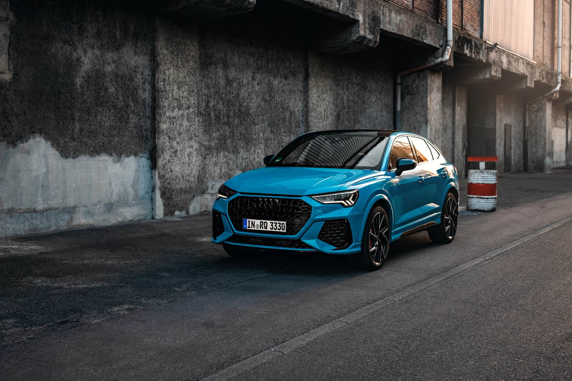 Blauer Kompakt-SUV vor verwitterter Betonwand in urbaner Umgebung, Automotive-Aufnahme im Abendlicht